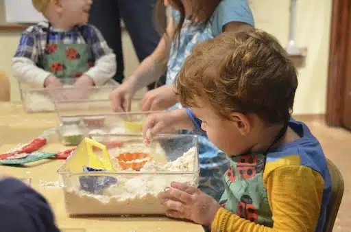 Children at a table engaging in sensory play with bins as part of the therapy process.