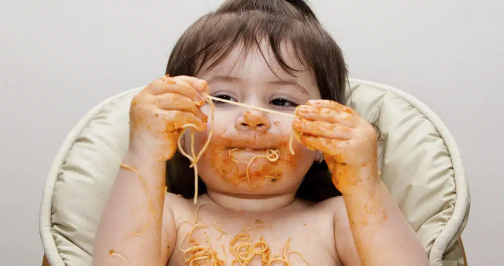 Child exploring sensory textures by playing with spaghetti, highlighting tactile sensory processing in early development