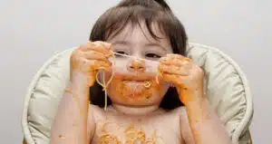 Child exploring sensory textures by playing with spaghetti, highlighting tactile sensory processing in early development