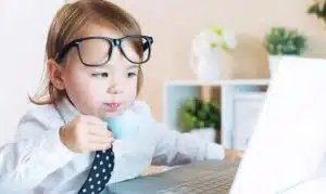 A comical image of a child dressed as an executive sipping a cup looking at a laptop showing the need for brain breaks to keep children focused.