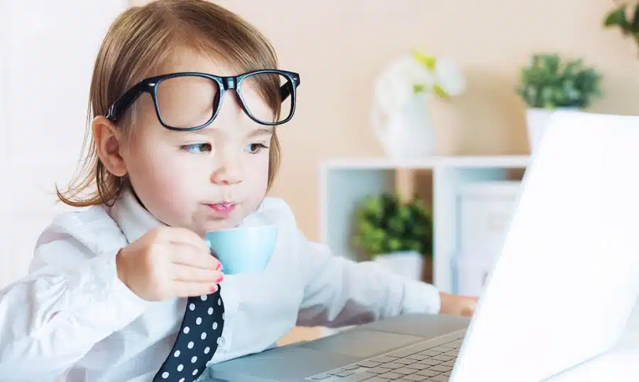 A comical image of a child dressed as an executive sipping a cup looking at a laptop showing the need for brain breaks to keep children focused.