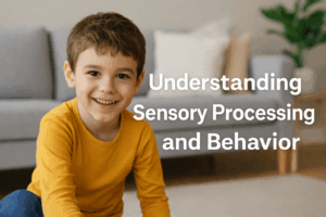 Smiling young boy in a yellow shirt sitting on the floor of a cozy living room, with text reading ‘Understanding Sensory Processing and Behavior’ overlayed beside him.